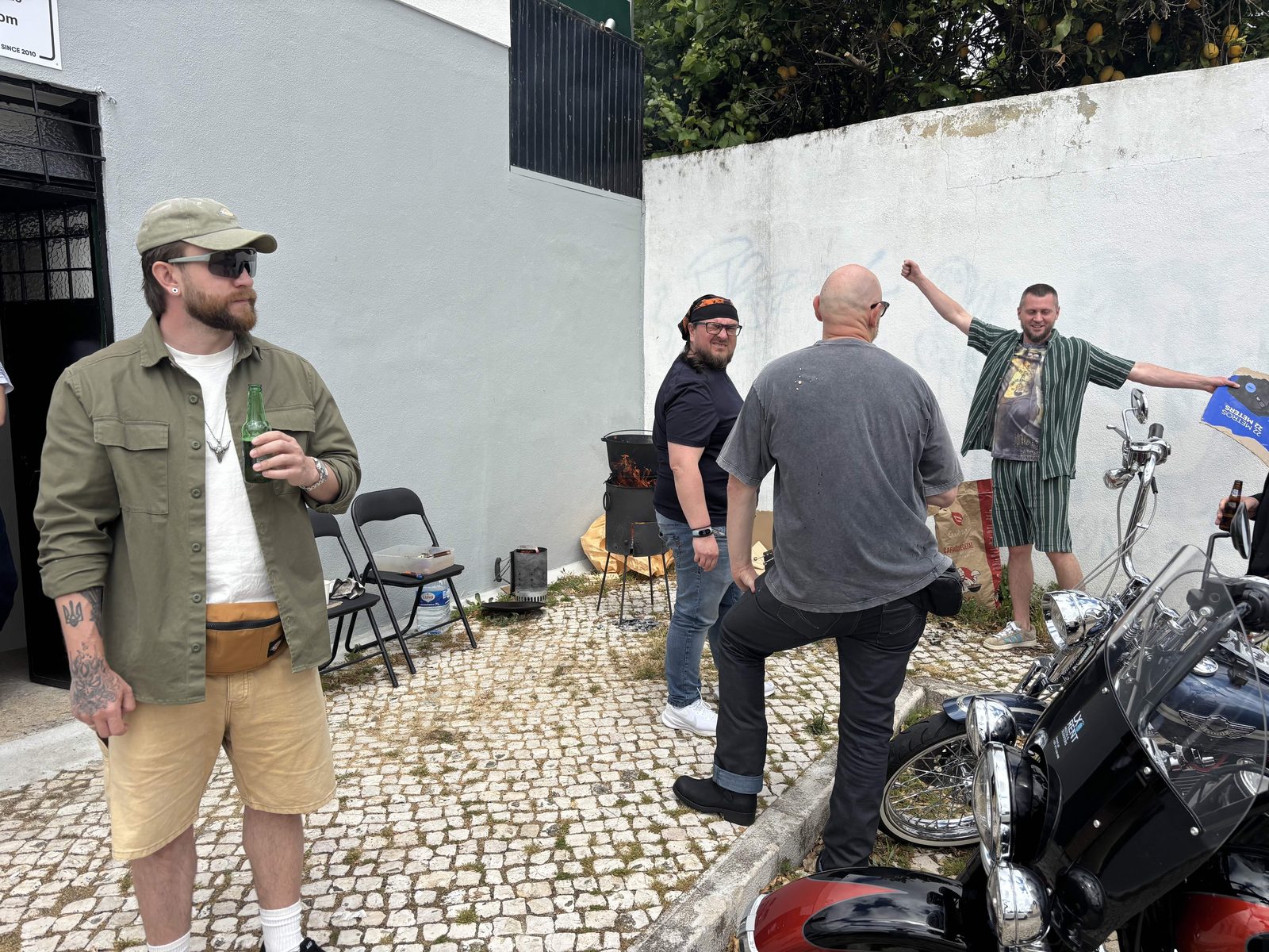 Байкери біля входу в майстерню Iron Custom Motors у Кашкайші у день відкриття, мотоцикли на бруківці.